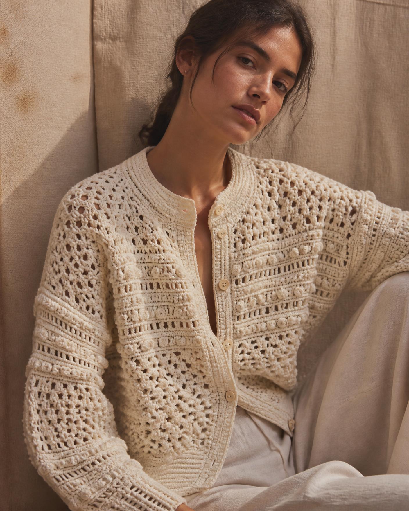 Model wearing a hand-crocheted cream cardigan in soft daylight